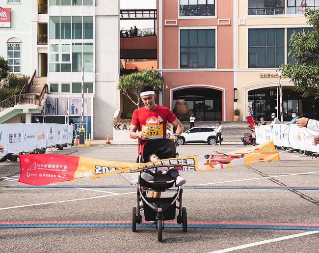 鐵人三項亞運選手張團畯肩負「鐵人奶爸」，推著女兒完成路跑活動